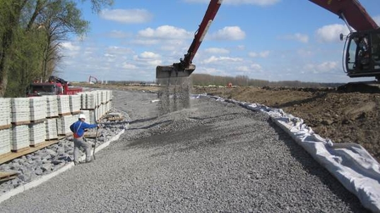 Medewerker kijkt toe hoe een graafmachine een dijk versterkt met stenen. | © waterschap Hollandse Delta