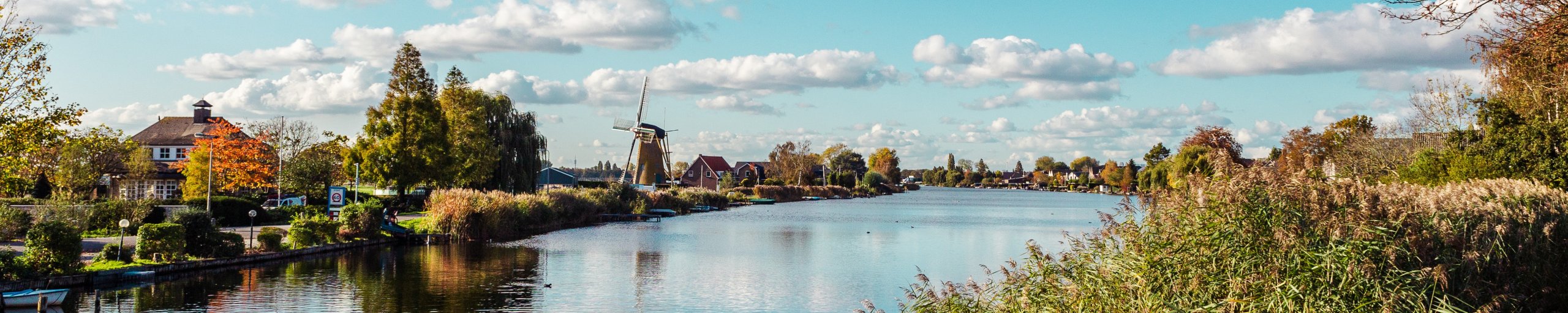 Vanaf de oever kijk je uit over de Waal. In de verste is een ouderwetse windmolen te zien