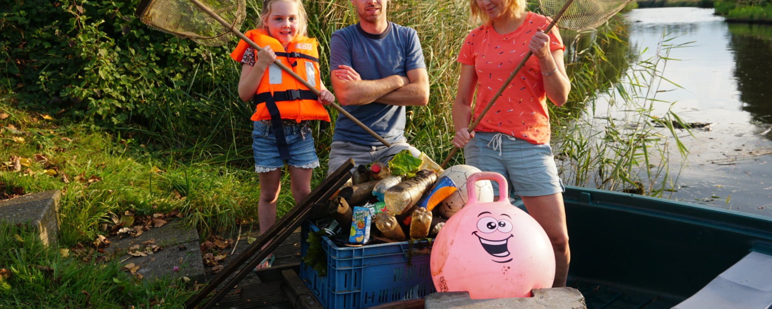 Jaap en zijn gezin scheppen afval uit het water