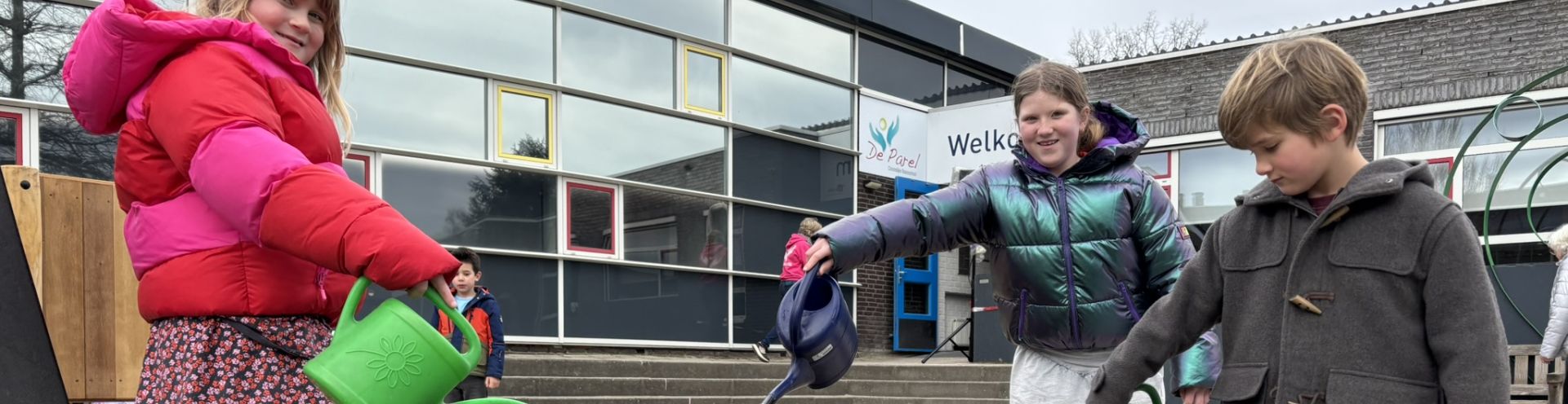 kinderen gieten water op een schoolplein